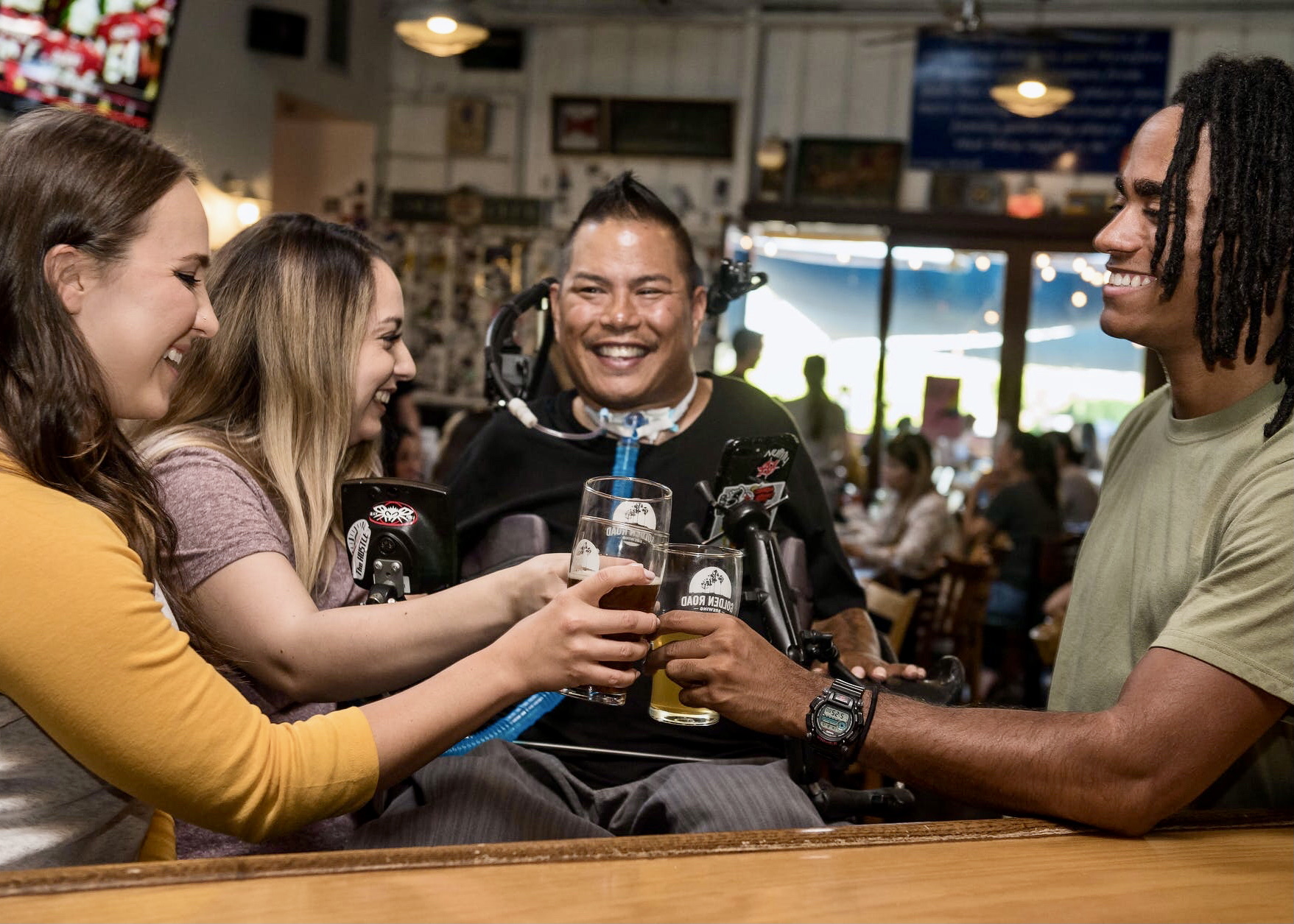 Een vrolijke groep mensen met en zonder beperking die proosten in een cafe.