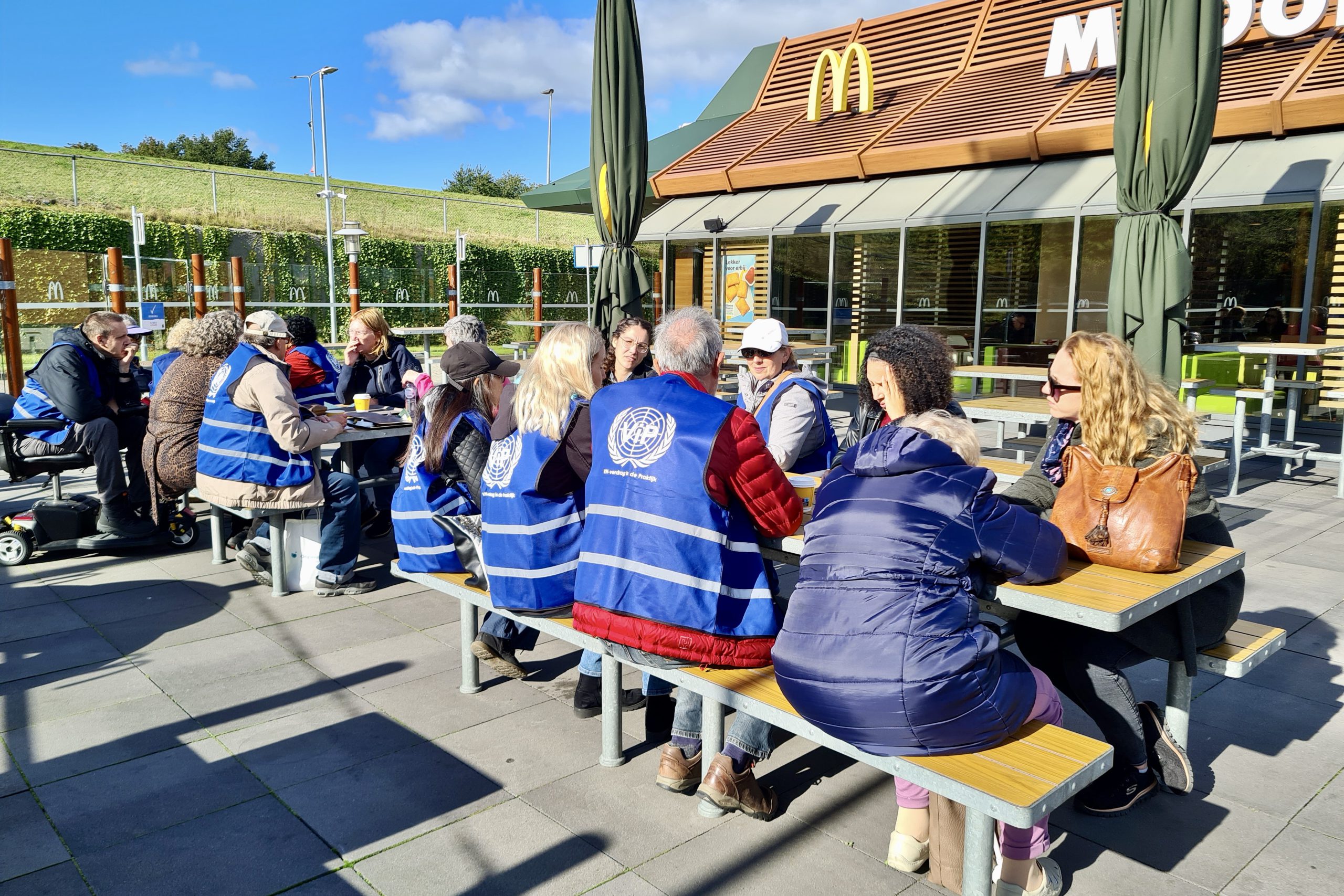 Deelnemers aan de busrit praten na op een terras